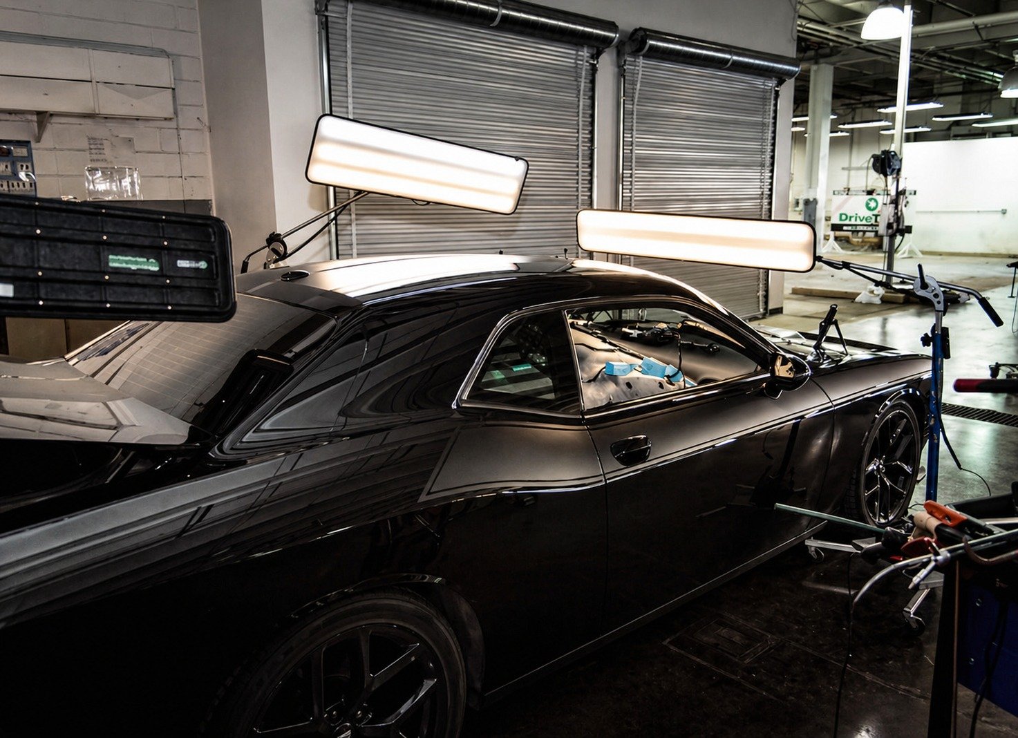 Black coupe in workshop being inspected for hail damage
